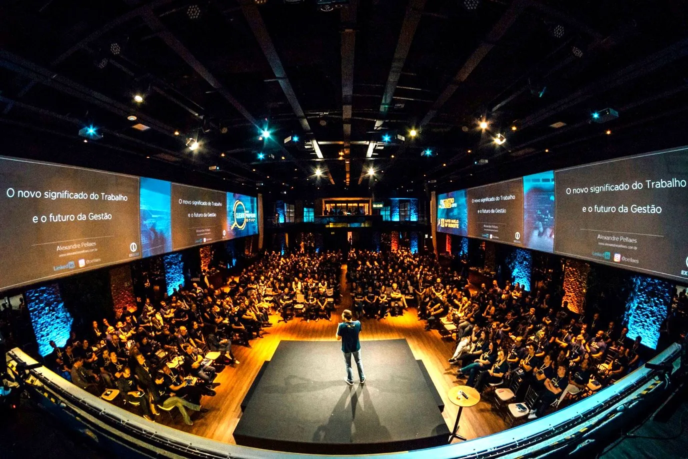 Sala conferenze gremita con il relatore sul palco e il titolo della sessione sugli schermi